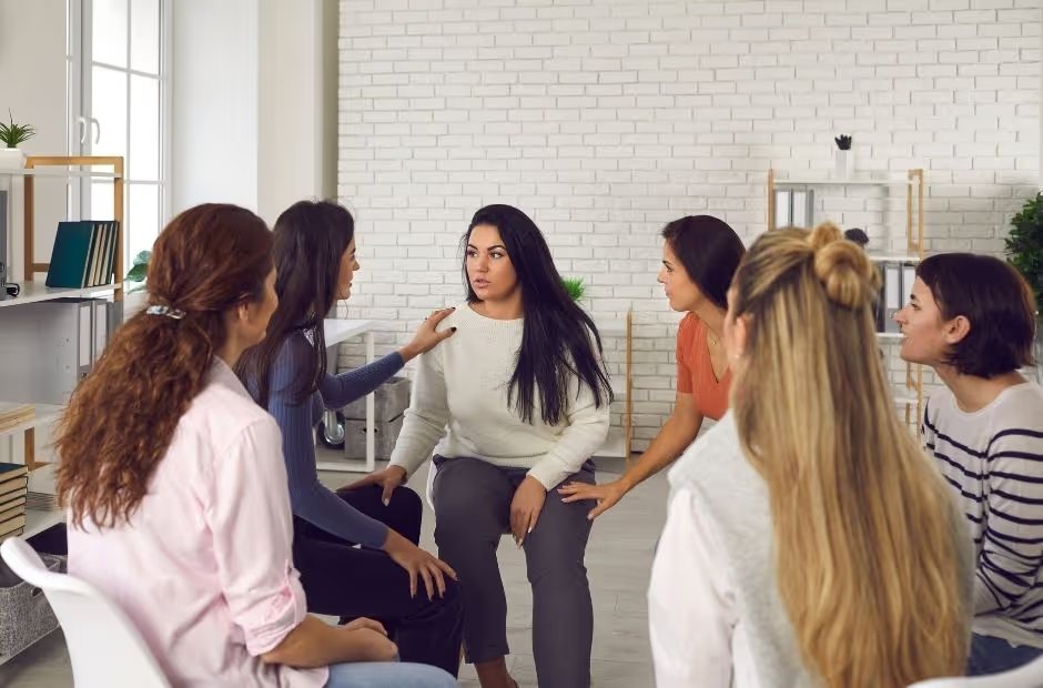 Mulheres conversando em roda em um espaço claro, partilhando experiências